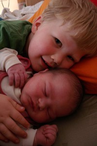 Foto von dem großen Bruder, der mit dem Neugeborenen kuschelt 